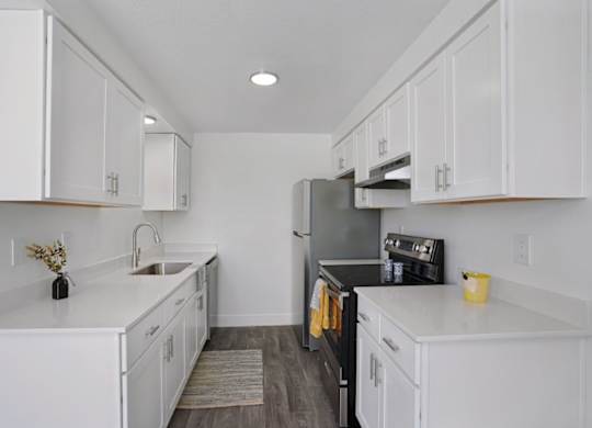A kitchen with white cabinets and a black refrigerator.