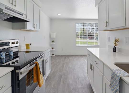 A kitchen with white cabinets and a black stove top.