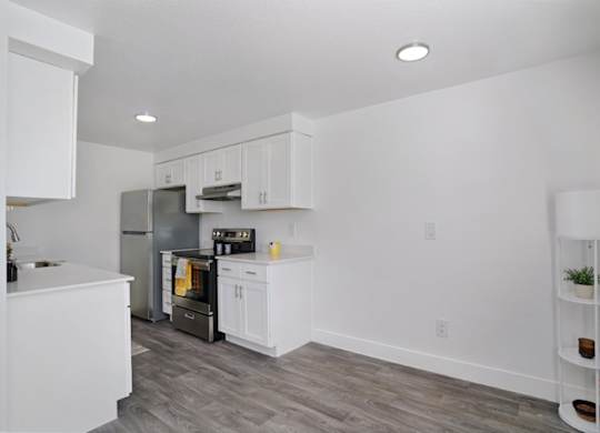 A kitchen with white cabinets and a grey refrigerator.