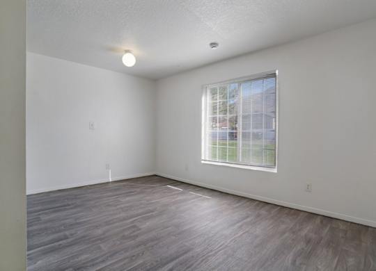 A room with a window and wooden flooring.