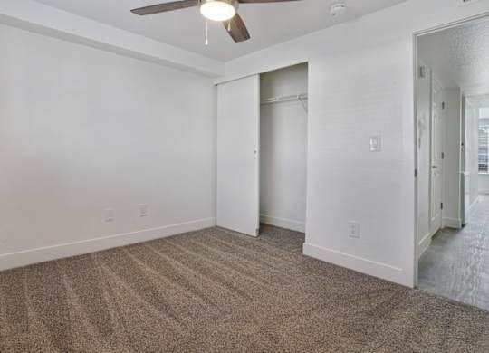 A room with a carpeted floor and a ceiling fan.