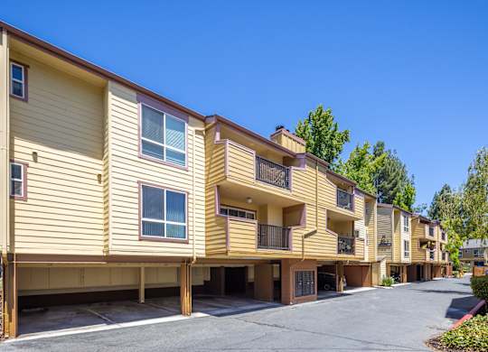 A row of tan apartment buildings with balconies and garages.