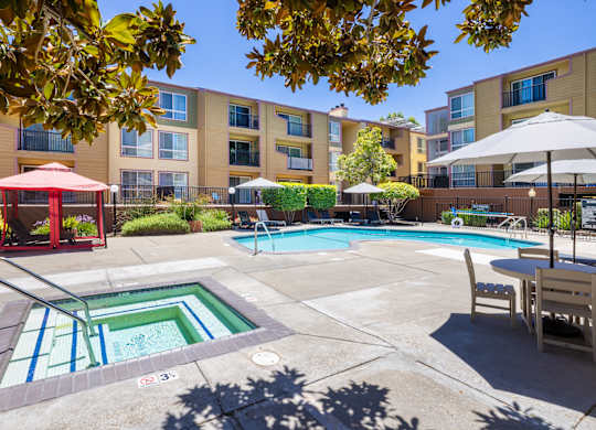 A pool area with a red gazebo and a table with chairs.