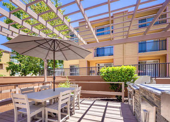 A patio with a table and chairs under a white umbrella.