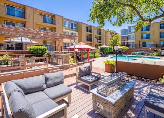 A sunny day at the poolside with a hot tub and lounging area.