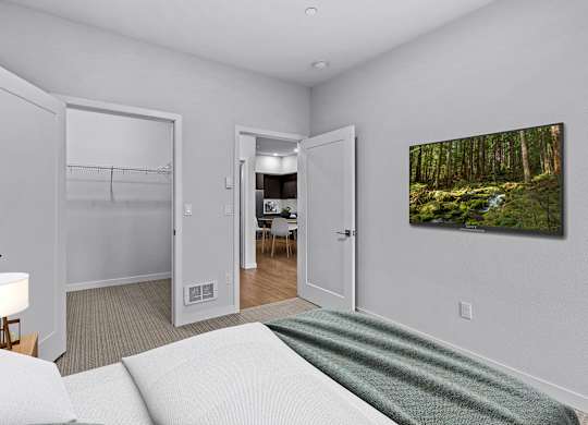 A living room with a white couch and a painting of a forest on the wall.