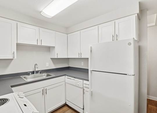 A white refrigerator is in a kitchen with white cabinets.