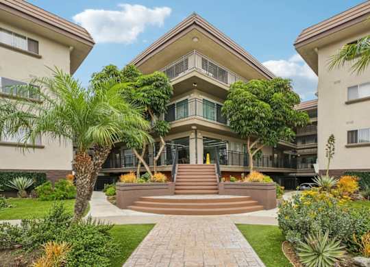 A large house with a front yard and a staircase leading to the entrance.
