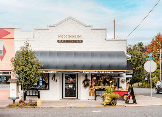 A white building with a black awning and a sign that says