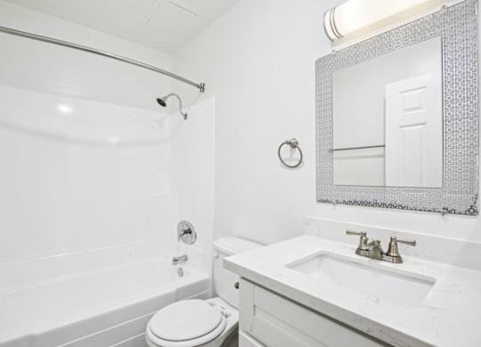 A white bathroom with a toilet, sink, and shower.