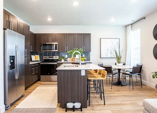 A modern kitchen with a refrigerator, sink, and dining table.