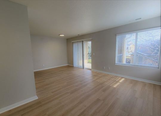 an empty living room with wood floors and a window