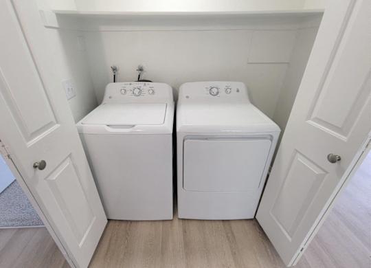 a washer and dryer in a laundry room with white cabinets