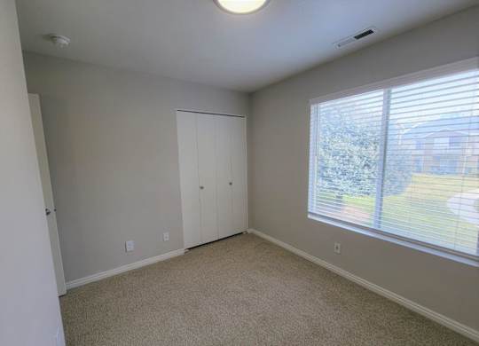 a bedroom with a large window and a closet