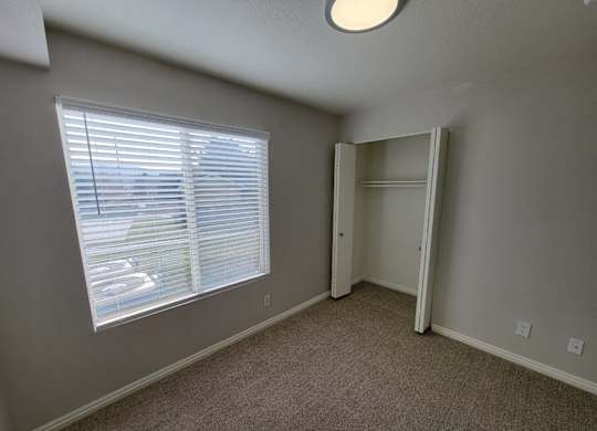 a bedroom with a large window and a closet