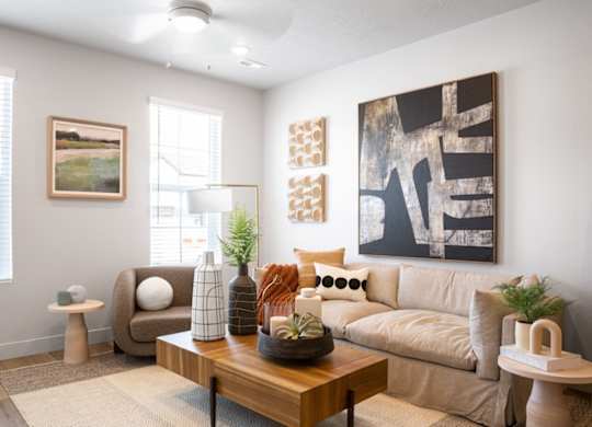 A living room with a brown couch, a wooden coffee table, and a large abstract painting on the wall.