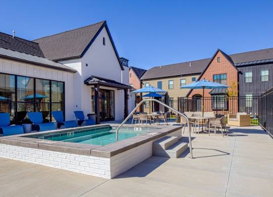 A pool area with a white building and blue chairs.