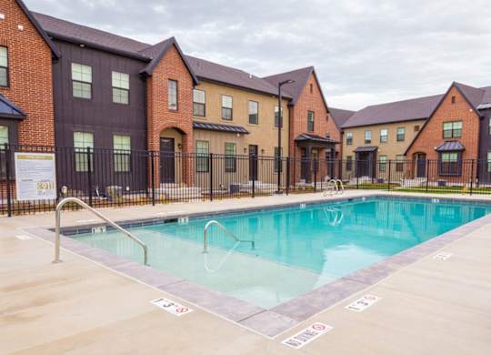 A swimming pool in front of a row of houses.