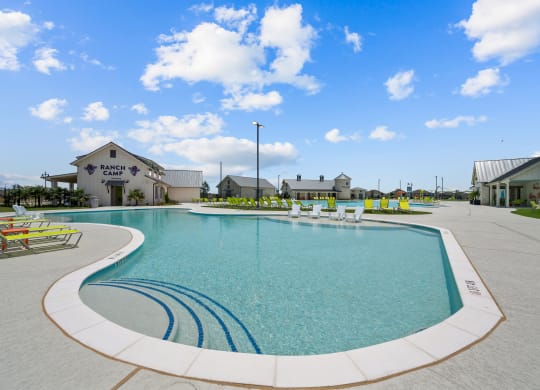 a large swimming pool with lounge chairs in front of a building