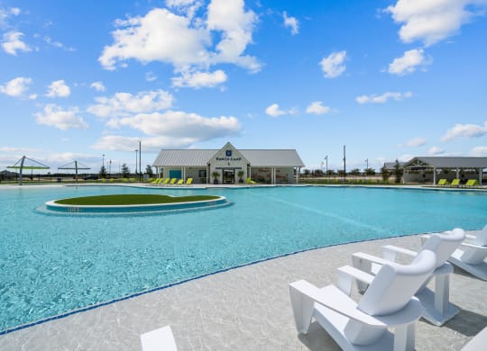 a large pool with white chairs and a building in the background