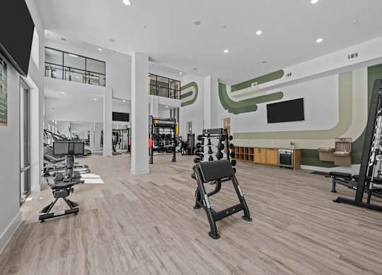 A gym with a variety of equipment including treadmills, weights, and exercise machines.