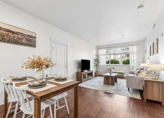A dining room with a wooden table and white chairs.
