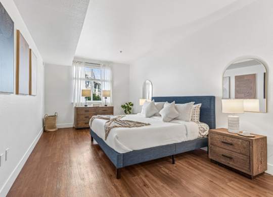 A bedroom with a bed, nightstand, and a window with curtains.