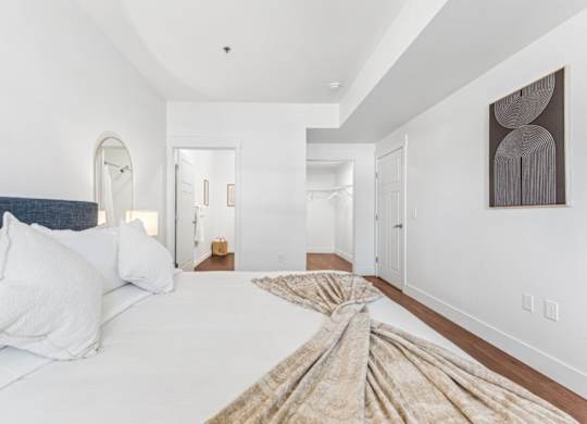 A bedroom with a large bed and a painting on the wall.