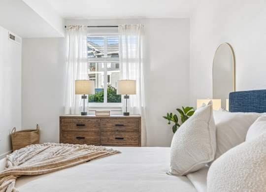 A bedroom with a large bed, a window with a view, and a wooden dresser.