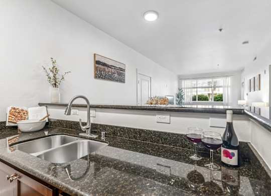 A kitchen with a granite countertop and a stainless steel sink.