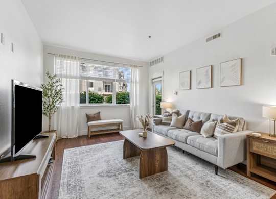 A living room with a grey couch, a wooden table, and a television.