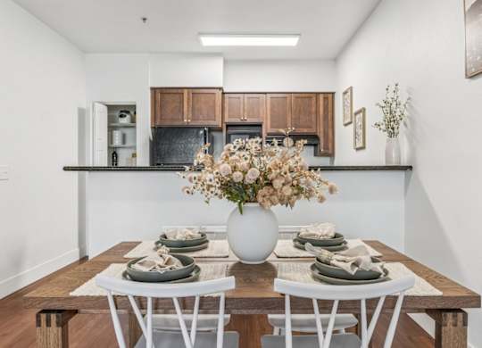 A dining table set with plates and a vase of flowers.