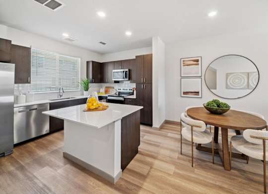 A modern kitchen with a white island and wooden floors.