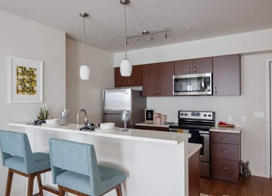 A kitchen with a white countertop and blue chairs.