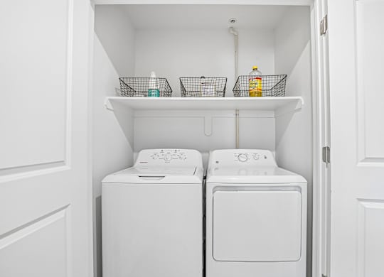 Two white washing machines in a small laundry room.
