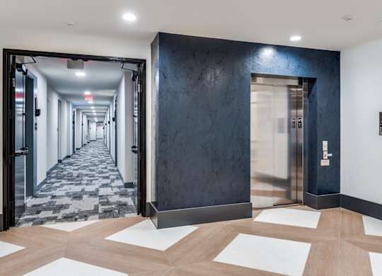 A hallway with a black wall and a tiled floor.