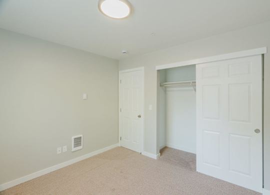A room with a white door and a carpeted floor.