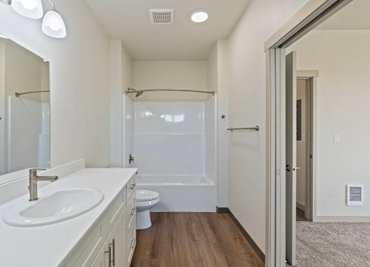 A white bathroom with a sink, toilet, and shower.