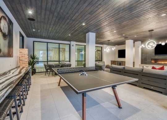 A ping pong table is in the middle of a room with a wooden ceiling.
