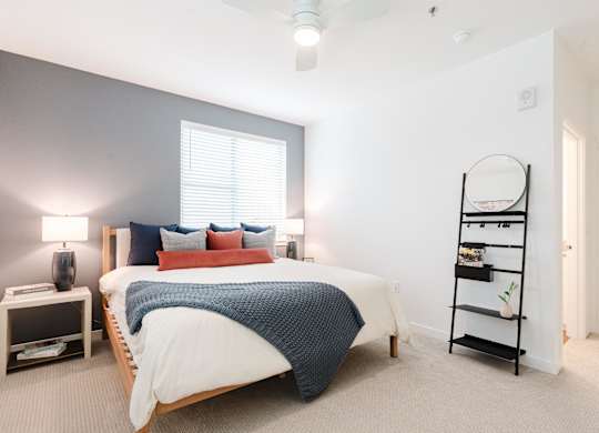 A bedroom with a bed, nightstand, and a window.