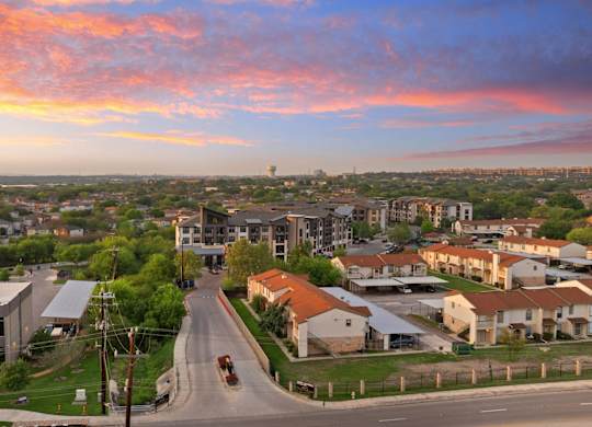 A sunset view of a residential area with houses and a road.