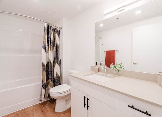 A white bathroom with a toilet, sink, and shower curtain.