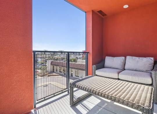 A patio with a couch and a table with a metal railing.