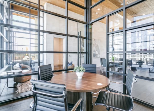 a conference room with glass walls and a wooden table and chairs