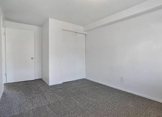 A room with white walls and a grey carpet.