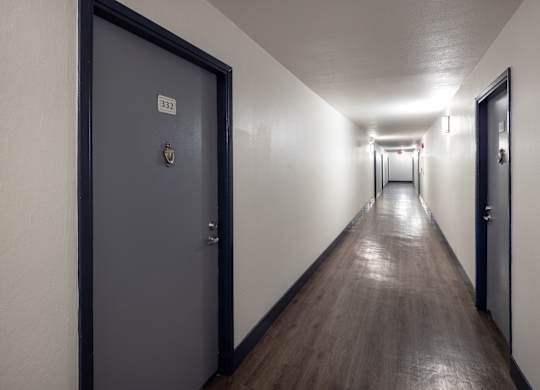 A long hallway with doors on either side and a sign on the wall.