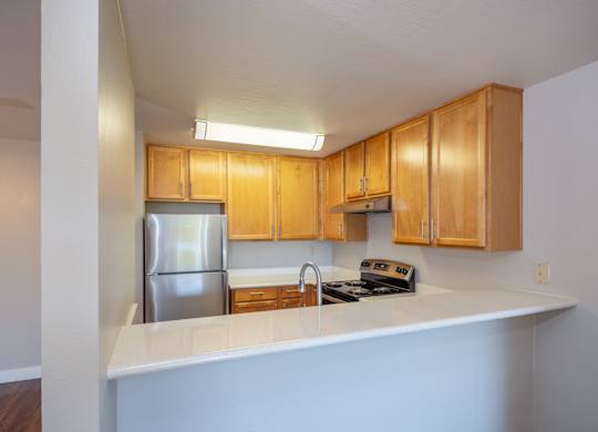 A kitchen with wooden cabinets and a stainless steel refrigerator.