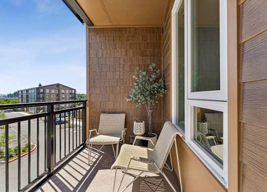 A balcony with chairs and a table with a plant on it.