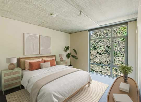 Bedroom with large windows looking at nature and trees at 2121 Belmont apartments in the Buckman neighborhood in Portland, Oregon.