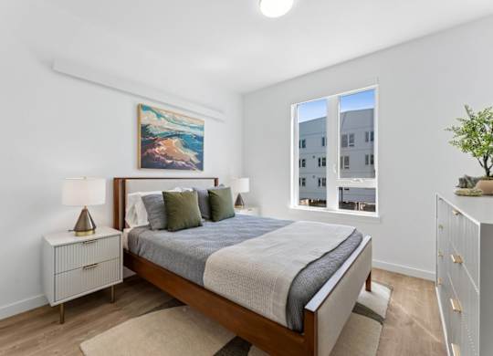 A bedroom with a large bed, a nightstand, and a painting on the wall.